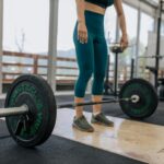 woman standing behind dumbbell preparing for deadlift